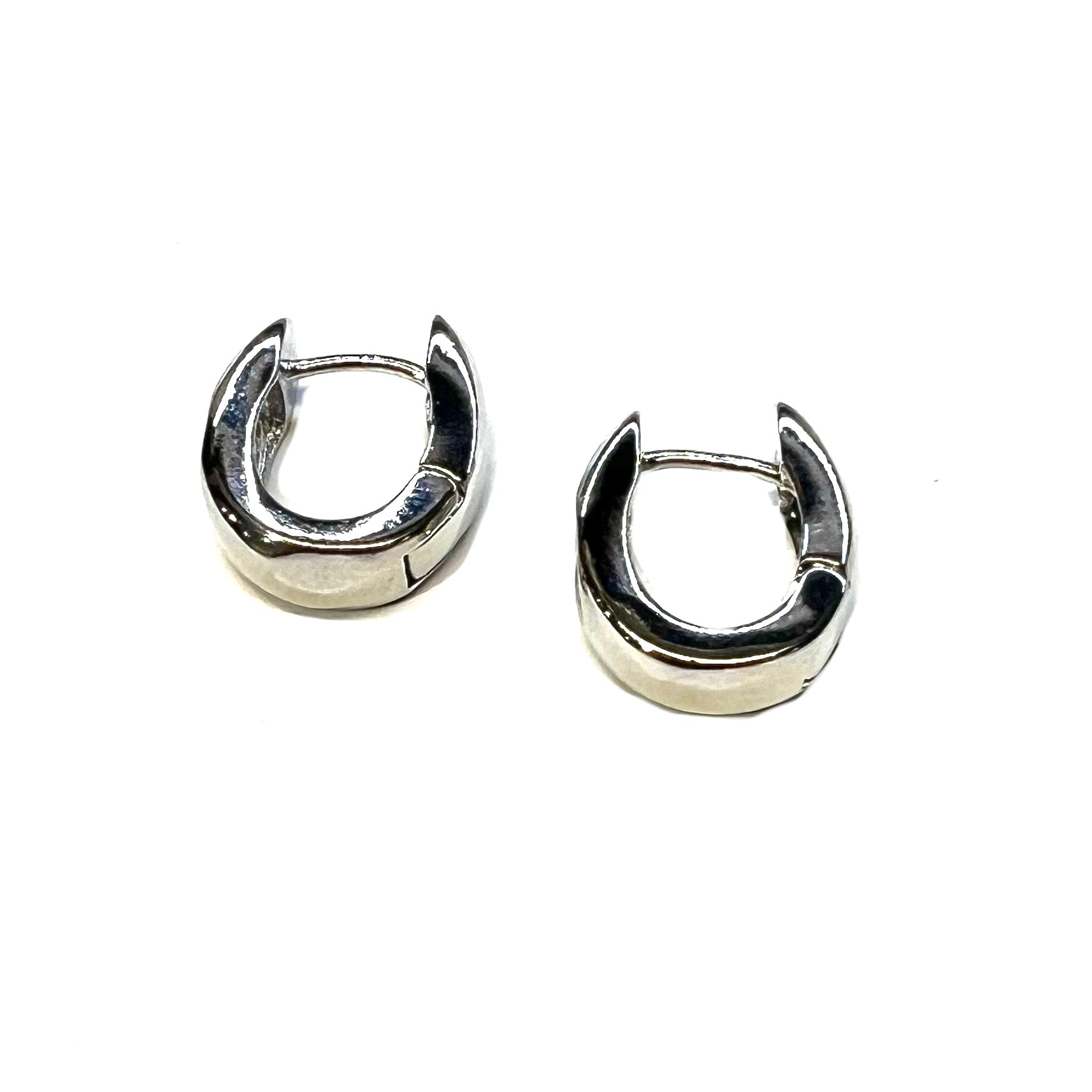Pair of silver cubic zirconia hoop earrings laying on their side, on a white background