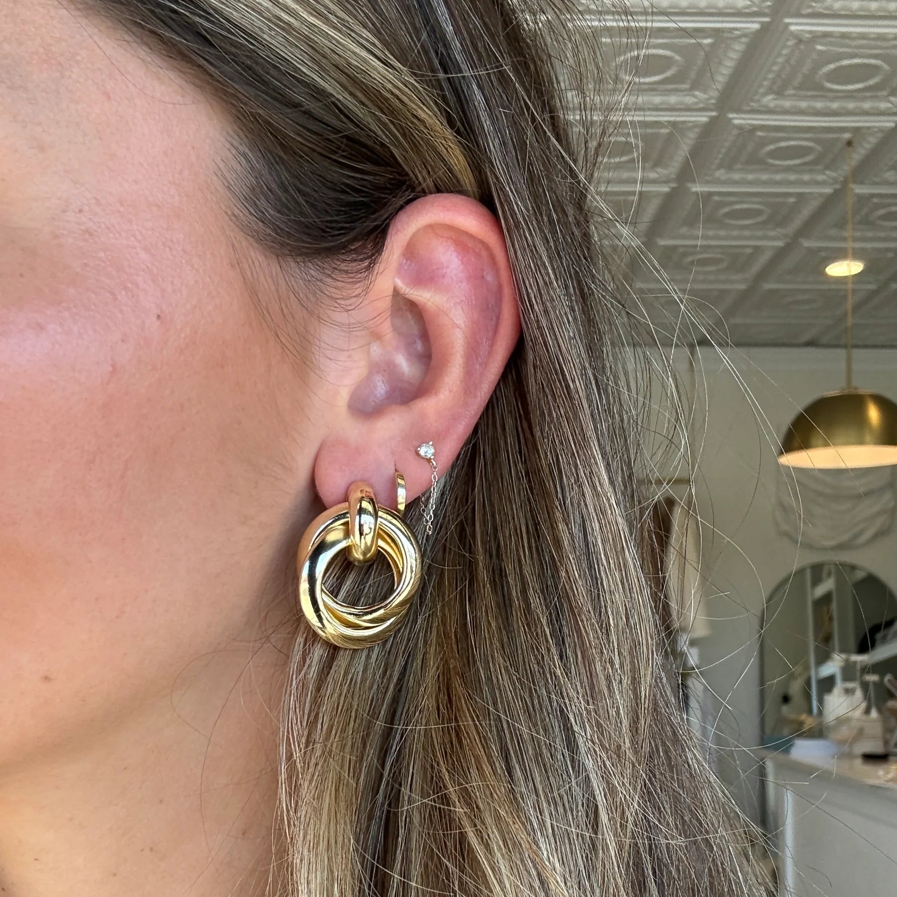 Person wearing a gold-colored twist knot earring