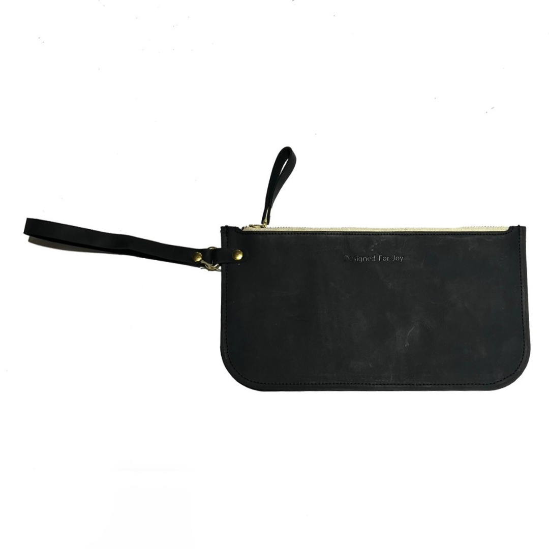 Black leather slim zipper wristlet with 'Designed for Joy' text, displayed on a white background