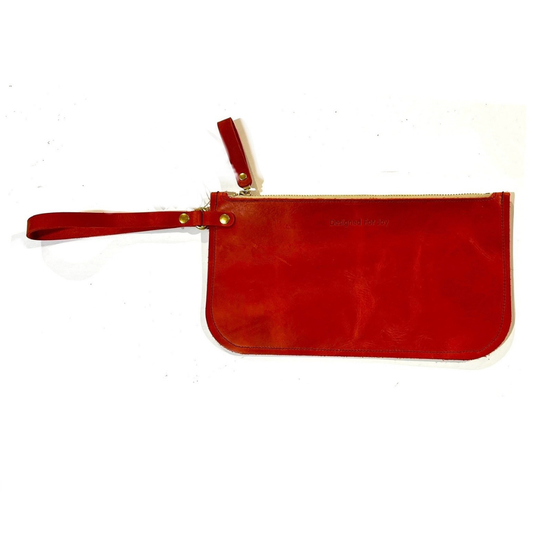 Persimmon red leather slim zipper wristlet with 'Designed for Joy' text, displayed on a white background