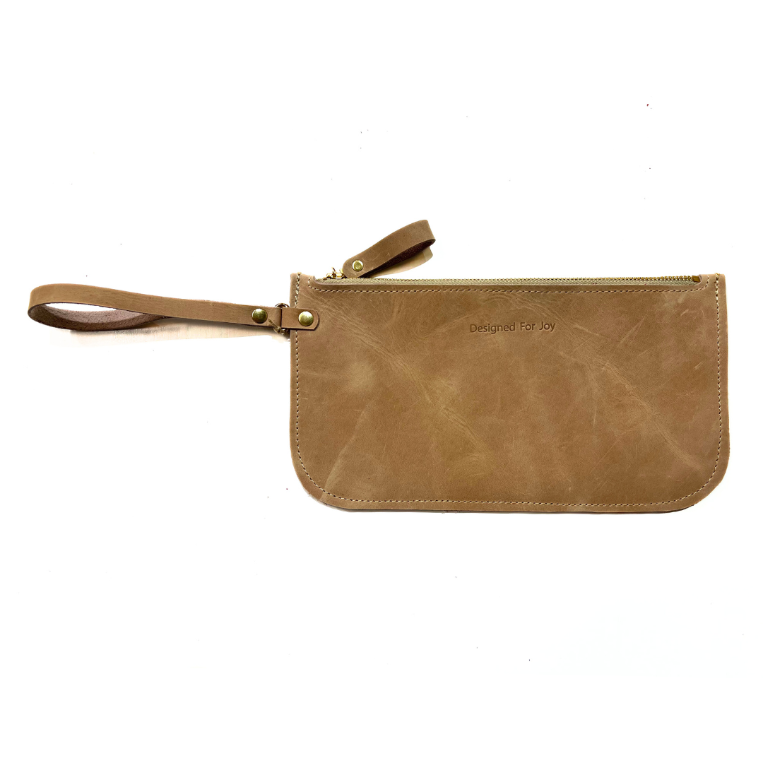 Tan leather slim zipper wristlet with 'Designed for Joy' text, displayed on a white background