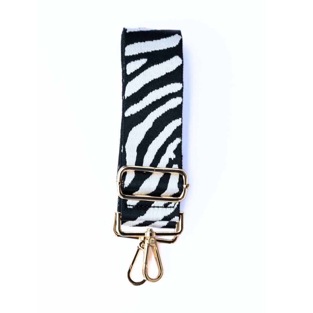 Black and white adjustable crossbody strap with a zebra pattern and metal hardware, displayed on a white background