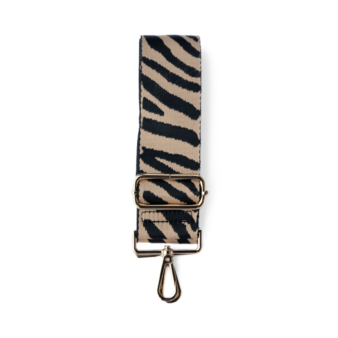 Tan and black adjustable crossbody strap with a zebra pattern and metal hardware, displayed on a white background