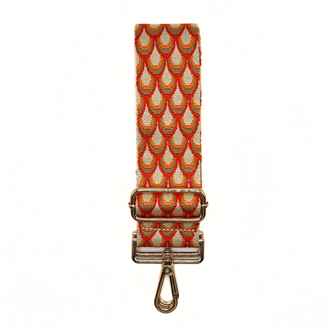 Orange adjustable crossbody strap with a scallop pattern and metal hardware, displayed on a white background