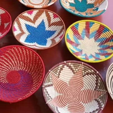 Colorful Rwandan baskets with floral patterns on a red surface