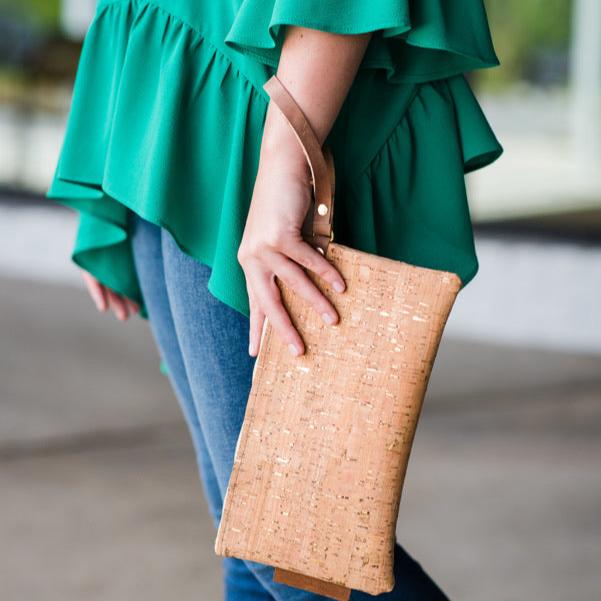 A side angle of a person holding a cork wristlet in an outdoor setting