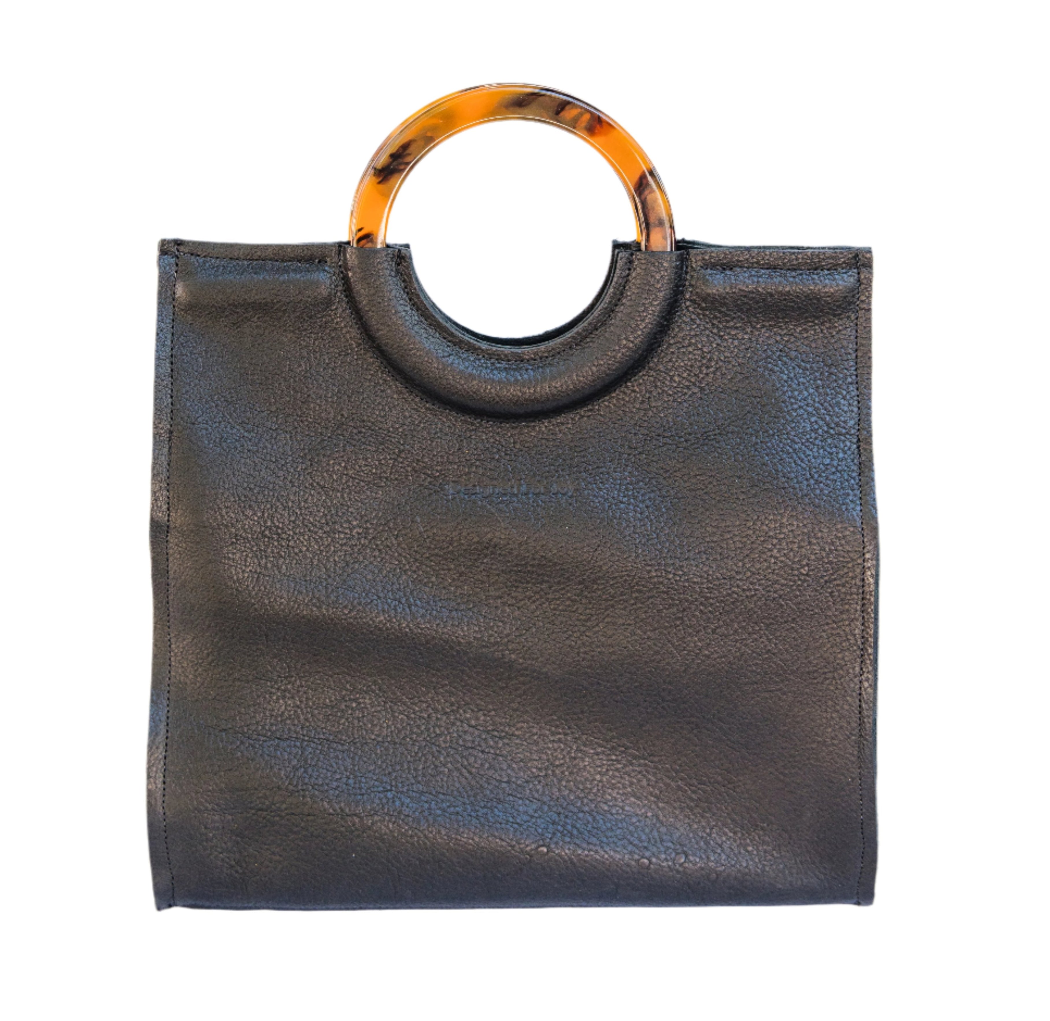 Black leather satchel handbag with round resin handles and a textured surface with 'Designed for Joy' text, displayed on a white background