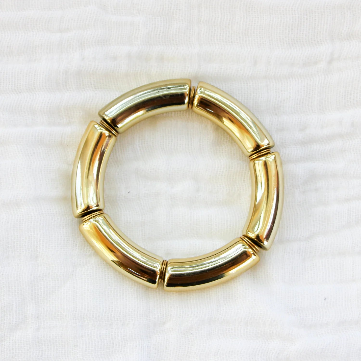 Bracelet featuring gold acrylic beads with spacers, displayed on a white fabric background
