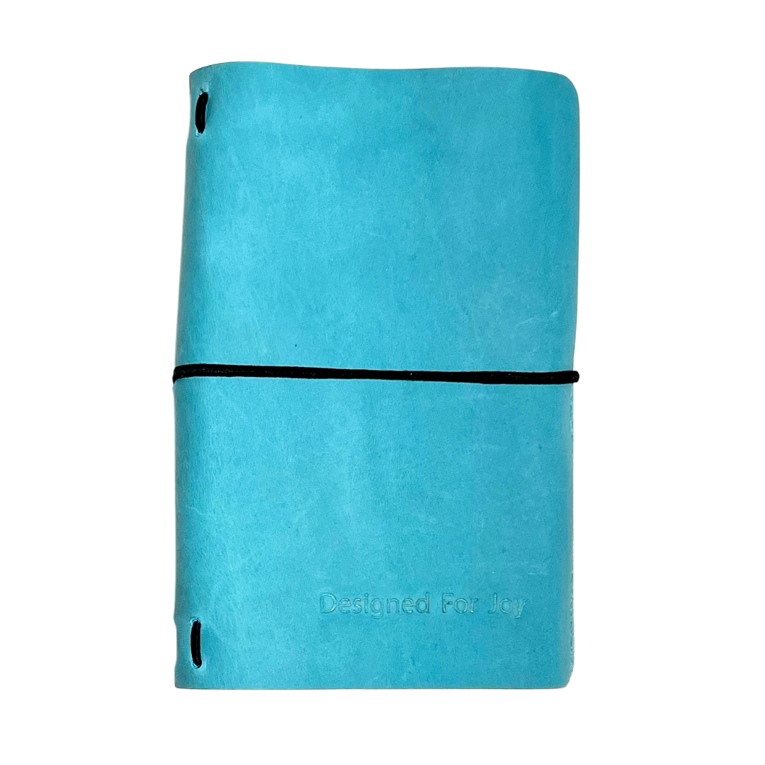 Aqua blue notebook with 'Designed for Joy' text on the cover and a black strap, on a white background