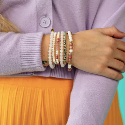 Close up of a person's wrist wearing multiple-colored bracelets
